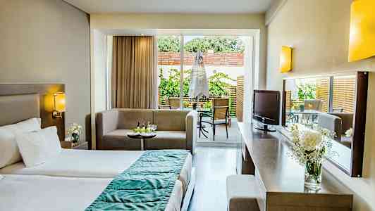 Et hotelværelse med en seng, siddeområde og adgang til en terrasse. (AI-genereret tekst)