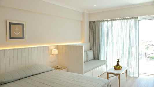 Et lyst soveværelse med en seng, en sofa og et bord med frugt. (AI-genereret tekst)