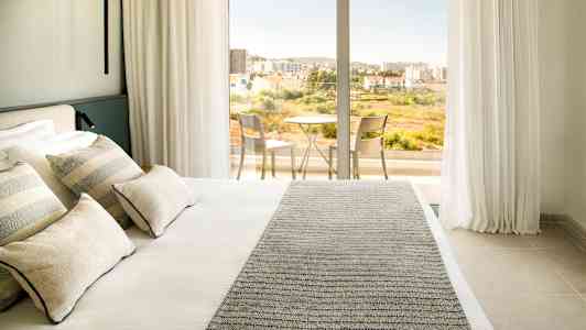 Hotelværelse med en dobbeltseng og adgang til balkon med bord og stole. (AI-genereret tekst)