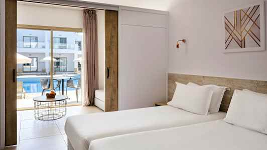 Hotelværelse med to enkeltsenge og udsigt til en udendørs pool og liggestole. (AI-genereret tekst)