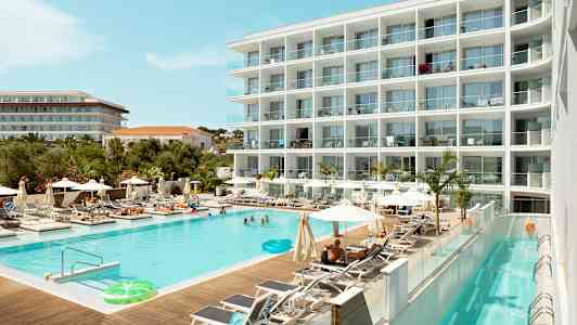 Et hotel med en swimmingpool omgivet af liggestole og parasoller. (AI-genereret tekst)