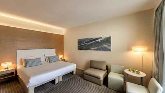 Hotelværelse med dobbeltseng, siddeområde og bord. (AI-genereret tekst)