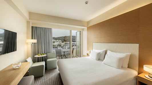 Hotelværelse med dobbeltseng, siddeområde og altan med udsigt. (AI-genereret tekst)