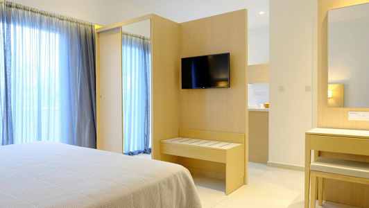 Hotelværelse med seng, TV på væggen og spejl ved et skrivebord. (AI-genereret tekst)