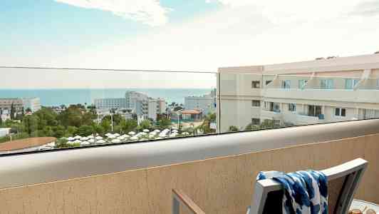 Udsigt fra balkon over hotelområde og hav. (AI-genereret tekst)