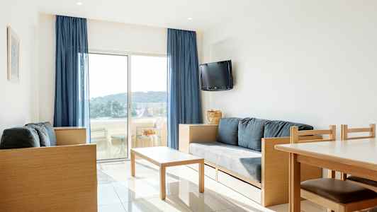 En lys stue med moderne møbler og udsigt til en balkon med landskab udenfor. (AI-genereret tekst)