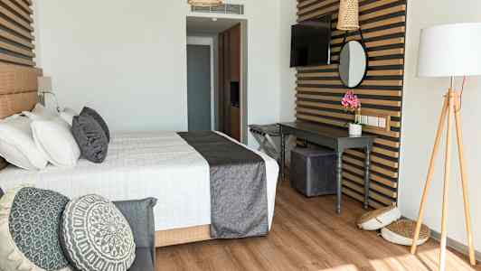 Et stilfuldt hotelværelse med en seng, dekorative puder og et skrivebord. (AI-genereret tekst)