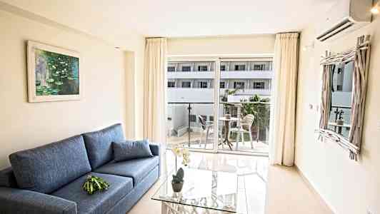 Interiør med en blå sofa, et glasbord og en altan med møbler. (AI-genereret tekst)