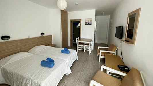 Hotelværelse med to enkeltsenge, bord med stole og en sofagruppe. (AI-genereret tekst)