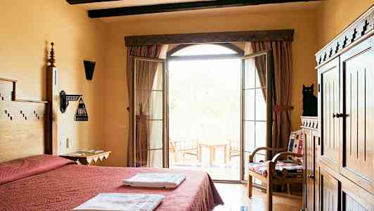 Et hotelværelse med dobbeltseng, håndklæder, træmøbler og en balkon med udsigt. (AI-genereret tekst)