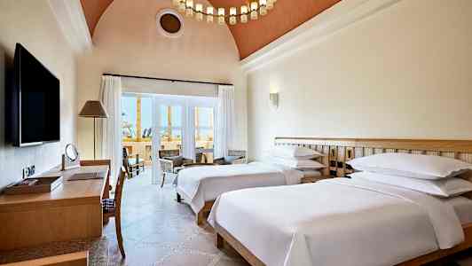 Hotelværelse med to enkeltsenge, skrivebord og siddeområde ved altanen. (AI-genereret tekst)