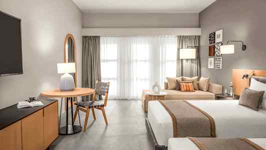 Moderne hotelværelse med to senge, siddeområde og et bord. (AI-genereret tekst)