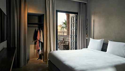 Hotelværelse med seng, balkon og garderobe. (AI-genereret tekst)