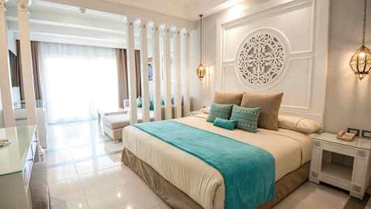 Et elegant hotelværelse indrettet med en stor seng, dekorative detaljer og bløde farver. (AI-genereret tekst)