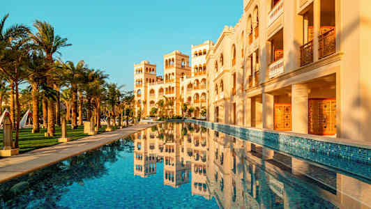 En bygning med arkitektoniske detaljer og en pool i forgrunden. (AI-genereret tekst)