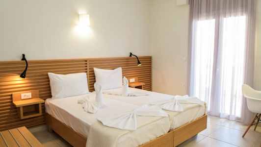 To senge med hvidt sengetøj, en træhovedgærde og dekorative håndklæder formet som svaner. (AI-genereret tekst)