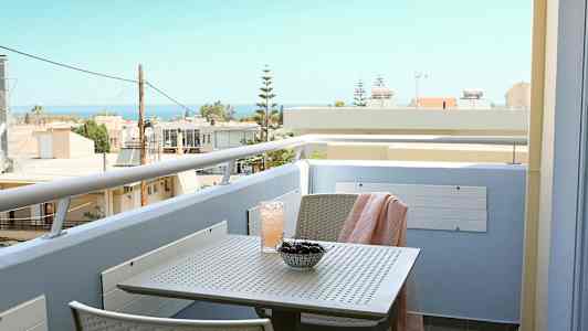 En balkon med udsigt mod havet, med et bord med kirsebær og en drik. (AI-genereret tekst)