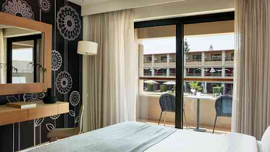 Et hotelværelse med balkon der vender ud mod en indre gårdhave. (AI-genereret tekst)