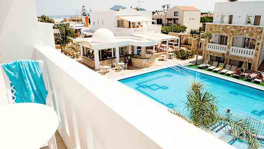 Udsigt fra en altan over en pool og hotelbygninger. (AI-genereret tekst)