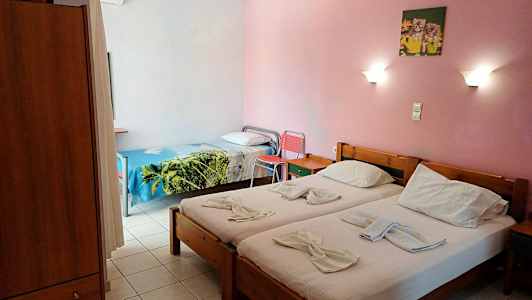 Billede af et hotelværelse med to enkeltsenge og en enkeltseng, lyserøde vægge og væglamper. (AI-genereret tekst)