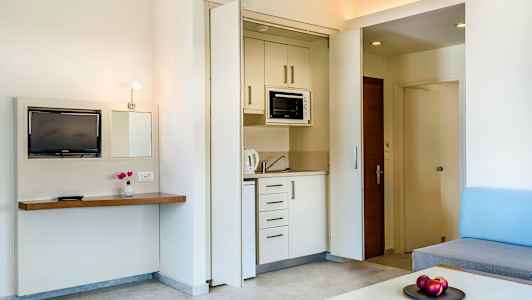 Et hotelværelse med et lille køkkenområde og stueindretning. (AI-genereret tekst)