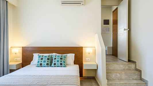 Indendørs billede af et soveværelse med en dobbeltseng, moderne indretning og en trappe nær sengen. (AI-genereret tekst)