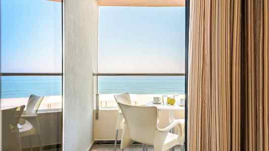 Altanudsigten med bord og stole samt havet i baggrunden. (AI-genereret tekst)