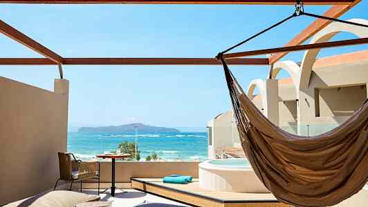 Tagterrasse med udsigt over havet, inkluderer hængekøje, bord og jacuzzi. (AI-genereret tekst)