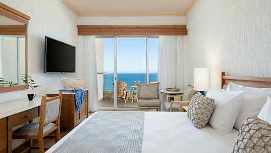 Hotelværelse med havudsigt gennem store glasdøre. (AI-genereret tekst)