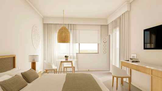 Et lyst hotelværelse med en stor seng, en hængende lampeskærm, et bord med to stole og et vægmonteret TV. (AI-genereret tekst)