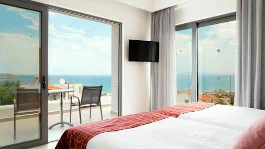 Hotelværelse med to senge og døre til balkon mod havet. (AI-genereret tekst)