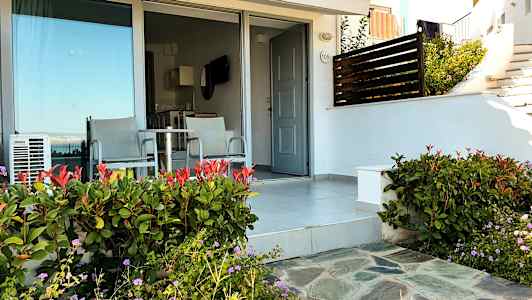 Terrasse med to stole og bord foran en dør og glasparti. (AI-genereret tekst)