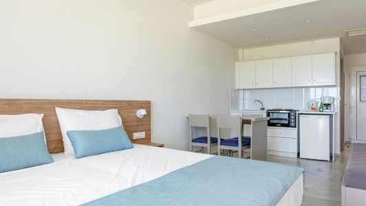 Et hotelværelse med en seng og en lille køkkenafdeling. (AI-genereret tekst)