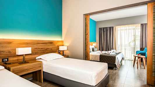 Hotelværelse med to enkeltsenge og udsigt til dobbeltseng gennem en åben portal. (AI-genereret tekst)