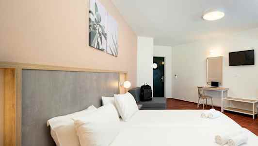 Hotelværelse med dobbeltseng, siddeområde, skrivebord og TV. (AI-genereret tekst)