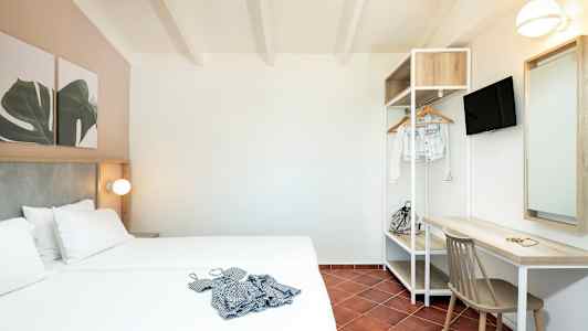 Et hotelværelse med dobbeltseng, skrivebord, stol og åben garderobe. (AI-genereret tekst)