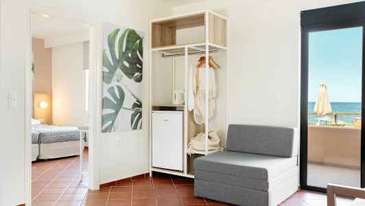 Moderne hotelværelse med siddeplads, åben garderobe og havudsigt. (AI-genereret tekst)