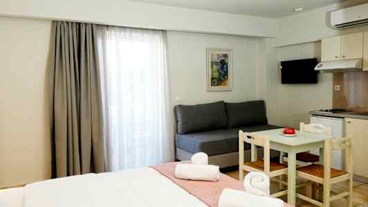 Et hotelværelse med en seng, en sofa, et spisebord med stole og et tekøkken. (AI-genereret tekst)