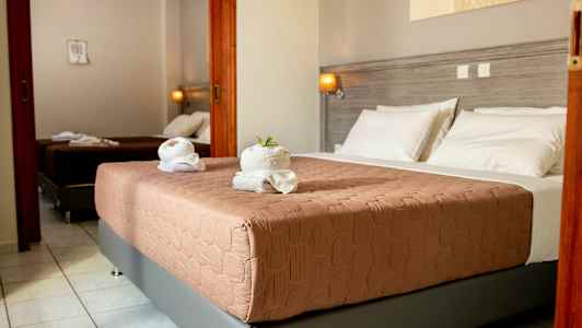 Hotelværelse med to senge, lysegrå vægge og hvidt sengetøj. (AI-genereret tekst)