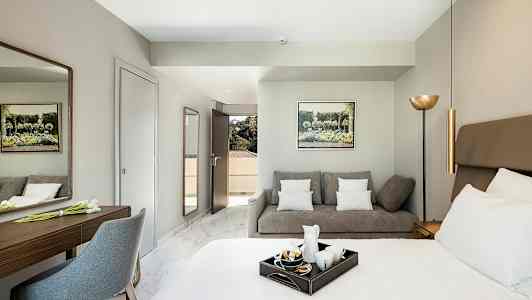 Et hotelværelse med en seng, en sofa og et skrivebord. (AI-genereret tekst)