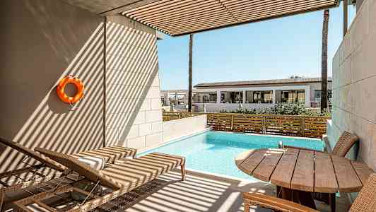 En privat terrasse med udsigt over en lille pool, liggestole og et bord med stole. (AI-genereret tekst)