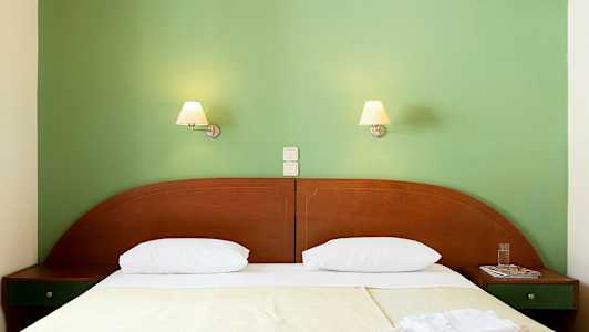 En seng med to sengelamper på en grøn væg. (AI-genereret tekst)