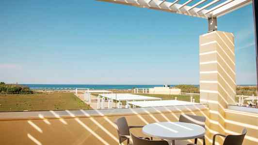 Udsigt fra en terrasse med havemøbler mod havet. (AI-genereret tekst)