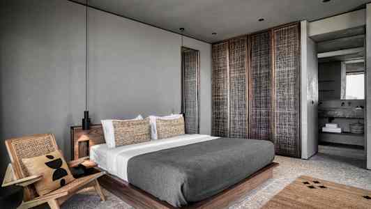 Moderne soveværelsesindretning med en stor seng og lænestol. (AI-genereret tekst)