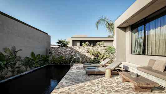 Et moderne udendørsområde med en stenpool, liggestole og planter omkring. (AI-genereret tekst)