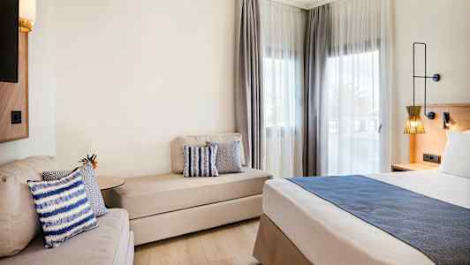 Moderne hotelværelse med seng, sofa og vinduer med lyse gardiner. (AI-genereret tekst)