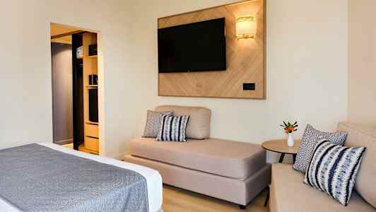 Et hotelværelse med sofa, seng og TV på væggen. (AI-genereret tekst)