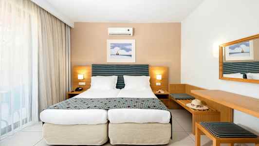 Standardværelse med to enkeltsenge, væglampe og spejl. (AI-genereret tekst)