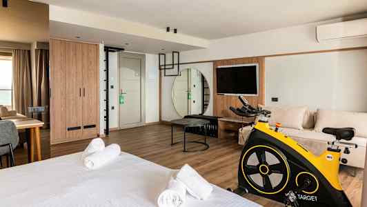 Et moderne hotelværelse med seng, siddeområde, motionscykel og TV. (AI-genereret tekst)