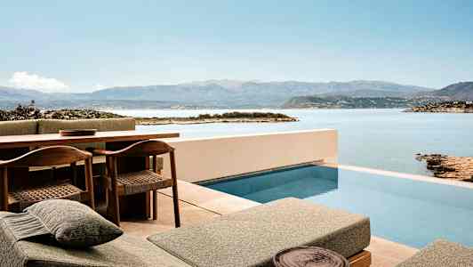 Terrasse med pool og udsigt over hav og bjerge. (AI-genereret tekst)